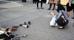 Fake rats eating fake pizza in front of a real New Yorker