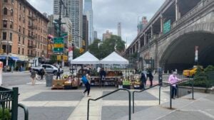 New York City street scene with a produce stand, pedestrians, traffic, and apartment buildings