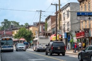 Staten Island neighborhood street scene with shops, traffic, and an MTA bu