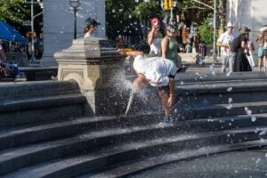 Man cooling off at a fountain during hot summer weather in New York City