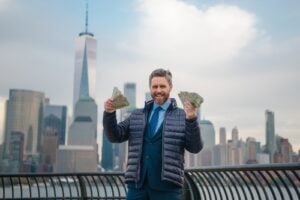 Man holding cash with the Lower Manhattan skyline in New York City