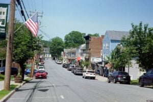 Downtown street scene in Montgomery, Orange County, New York, with shops, parked cars, and an American flag