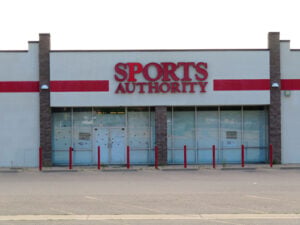 Closed Sports Authority storefront with paper-covered windows and the familiar red Sports Authority sign