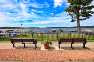 View of Chautauqua Lake from Bemus Point, New York, with waterfront benches, boats, and docks