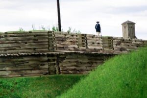 Revolutionary War interpreter standing on the reconstructed wooden fortifications at Fort Stanwix in Rome, New York