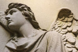 Close-up of a carved stone angel with detailed wings on a grave at Mount Hope Cemetery in Rochester, New York.