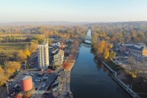 Aerial view of the Erie Canal running through historic Pittsford Village in Monroe County, New York, surrounded by autumn foliage.