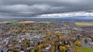 Aerial view of Skaneateles, New York, showing autumn foliage, village buildings, and the surrounding countryside beneath cloudy skies.