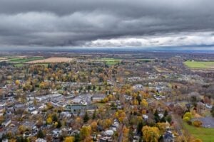 Aerial view of Skaneateles, New York, showing autumn foliage, village buildings, and the surrounding countryside beneath cloudy skies.