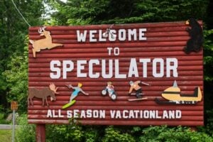 Wooden Welcome to Speculator sign decorated with Adirondack wildlife illustrations in Speculator, Hamilton County, New York.